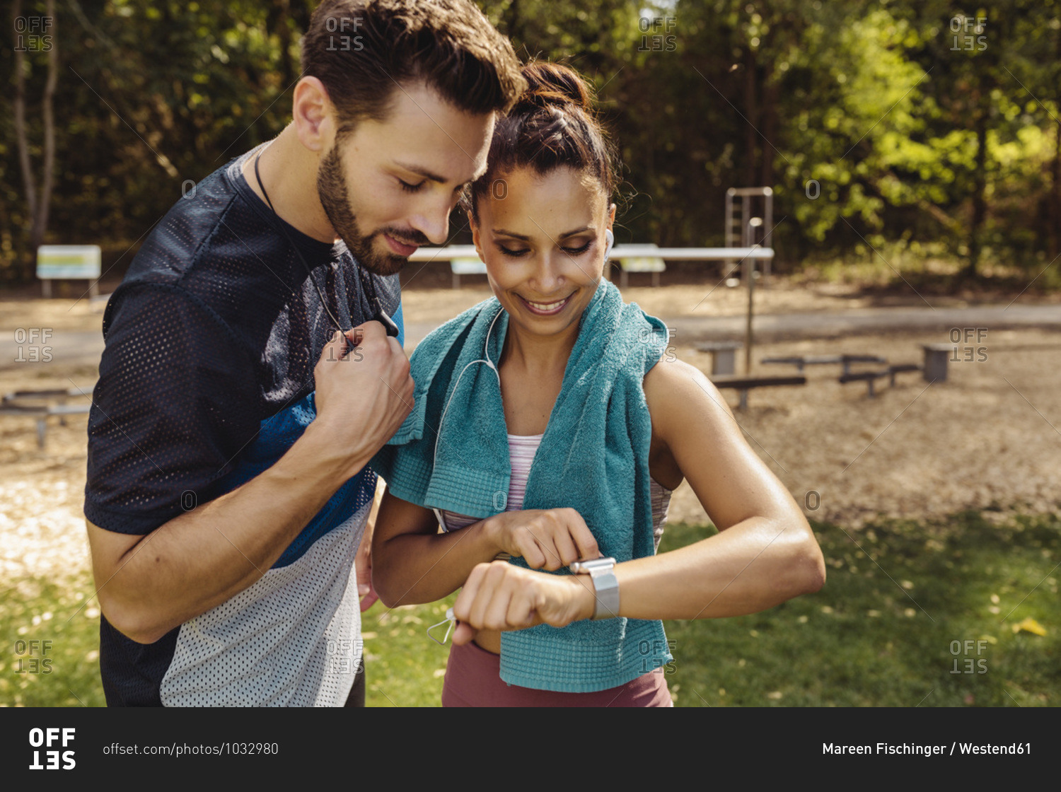 Sporty man and woman looking at a smartwatch in a park