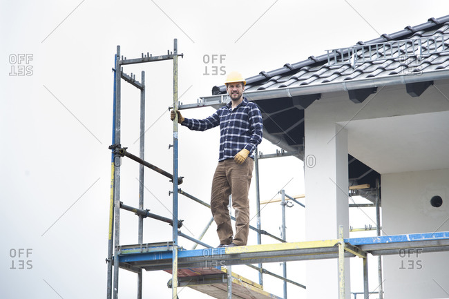 Construction worker standing on scaffold against clear sky at construction site