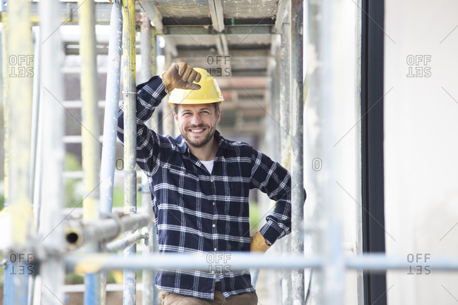 Smiling construction worker wearing helmet standing by scaffold at construction site