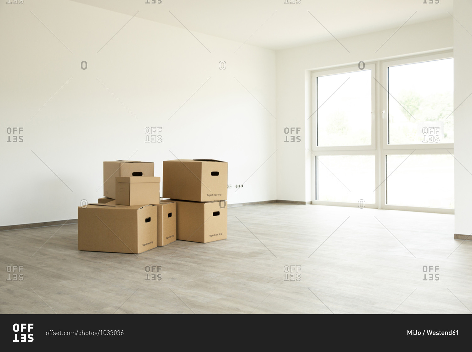 Cardboard boxes on hardwood floor against white wall in new house