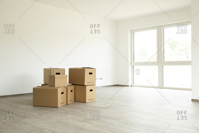 Cardboard boxes on hardwood floor against white wall in new house