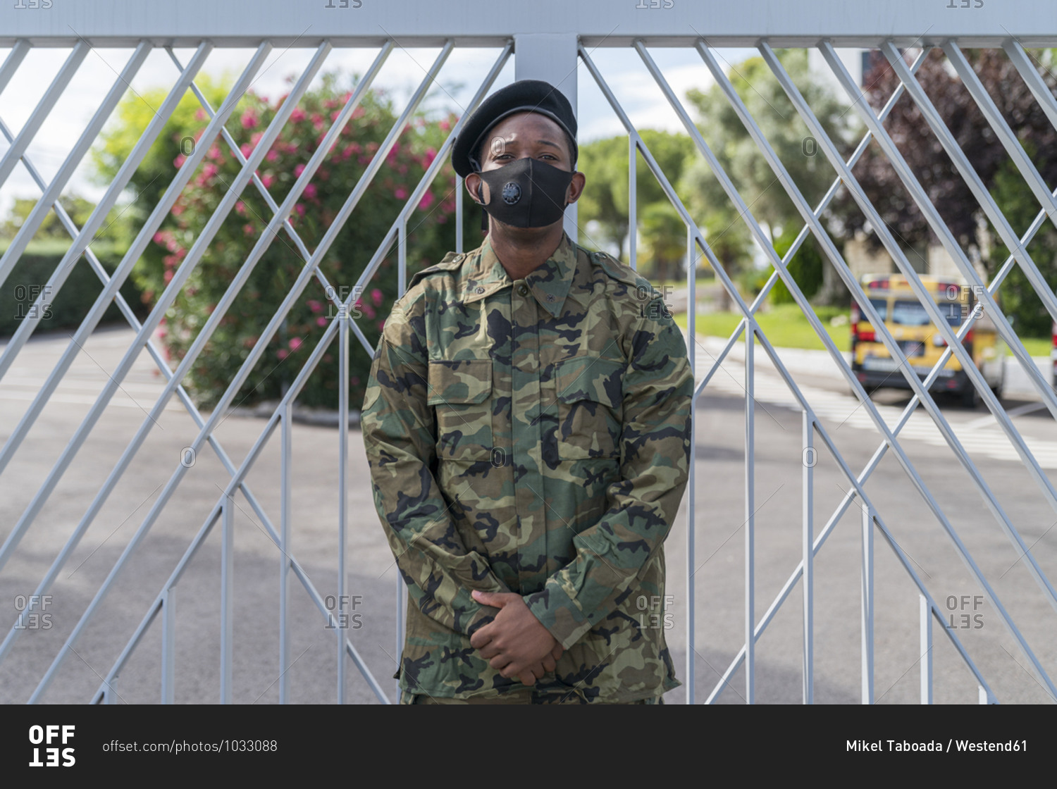 Army soldier wearing protective face mask while standing against gate