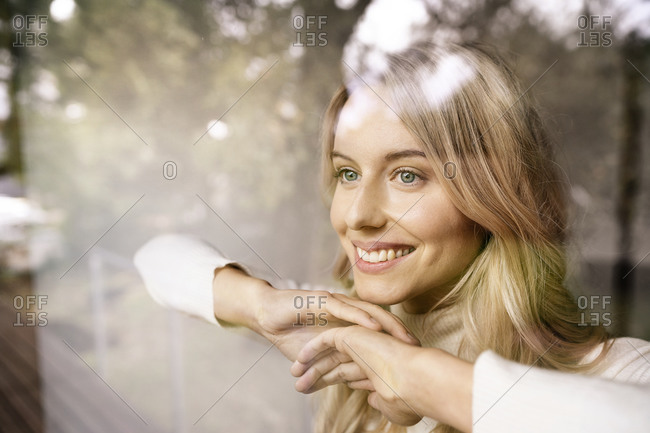 Close-up of thoughtful smiling businesswoman looking through window seen through glass