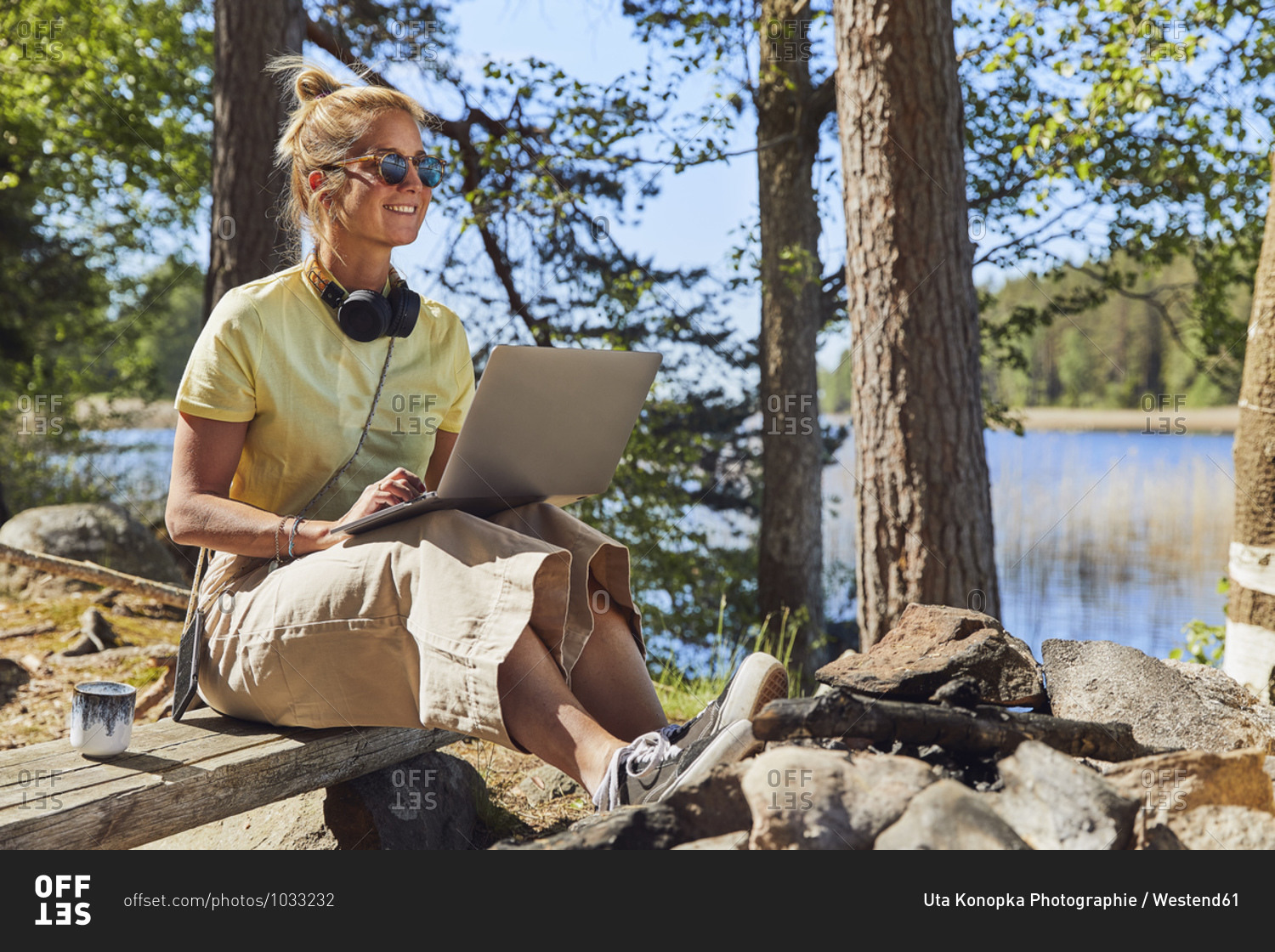 Mid adult woman wearing sunglasses using laptop while sitting in Tiveden National Park- Sweden