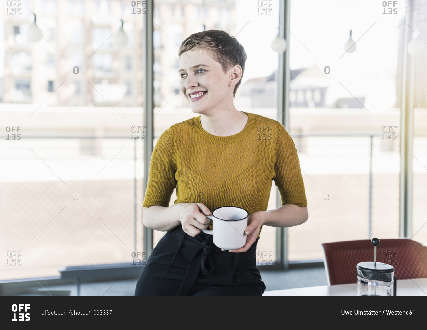 Smiling businesswoman in office holding coffee mug