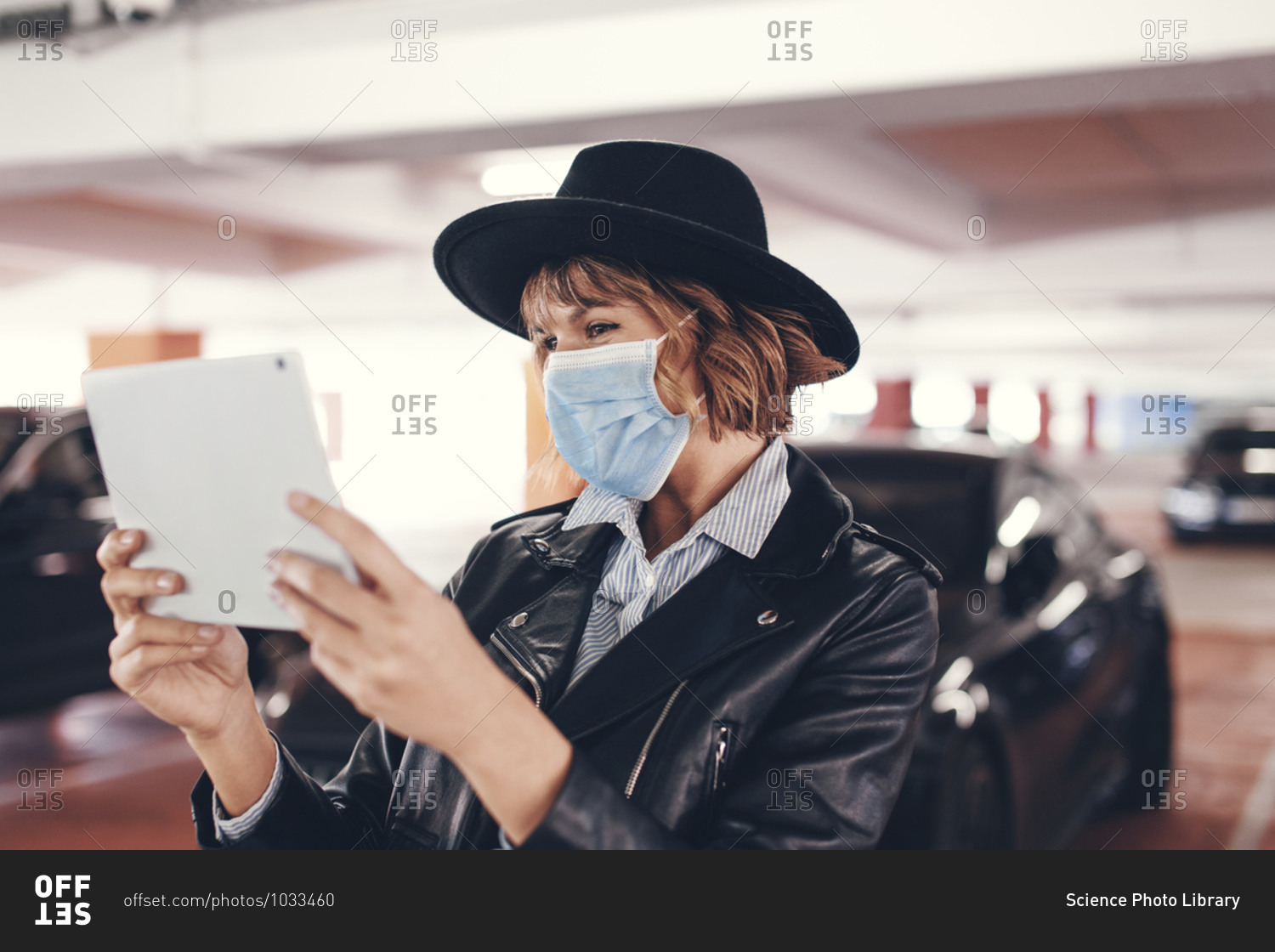 Young urban woman in mask and hat using tablet.