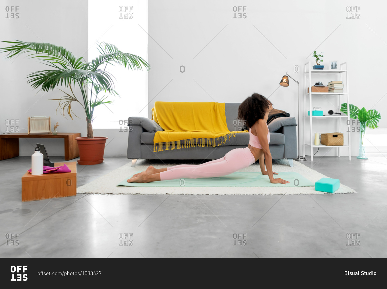 Fit woman practicing cobra pose using online yoga training program in the tablet at home