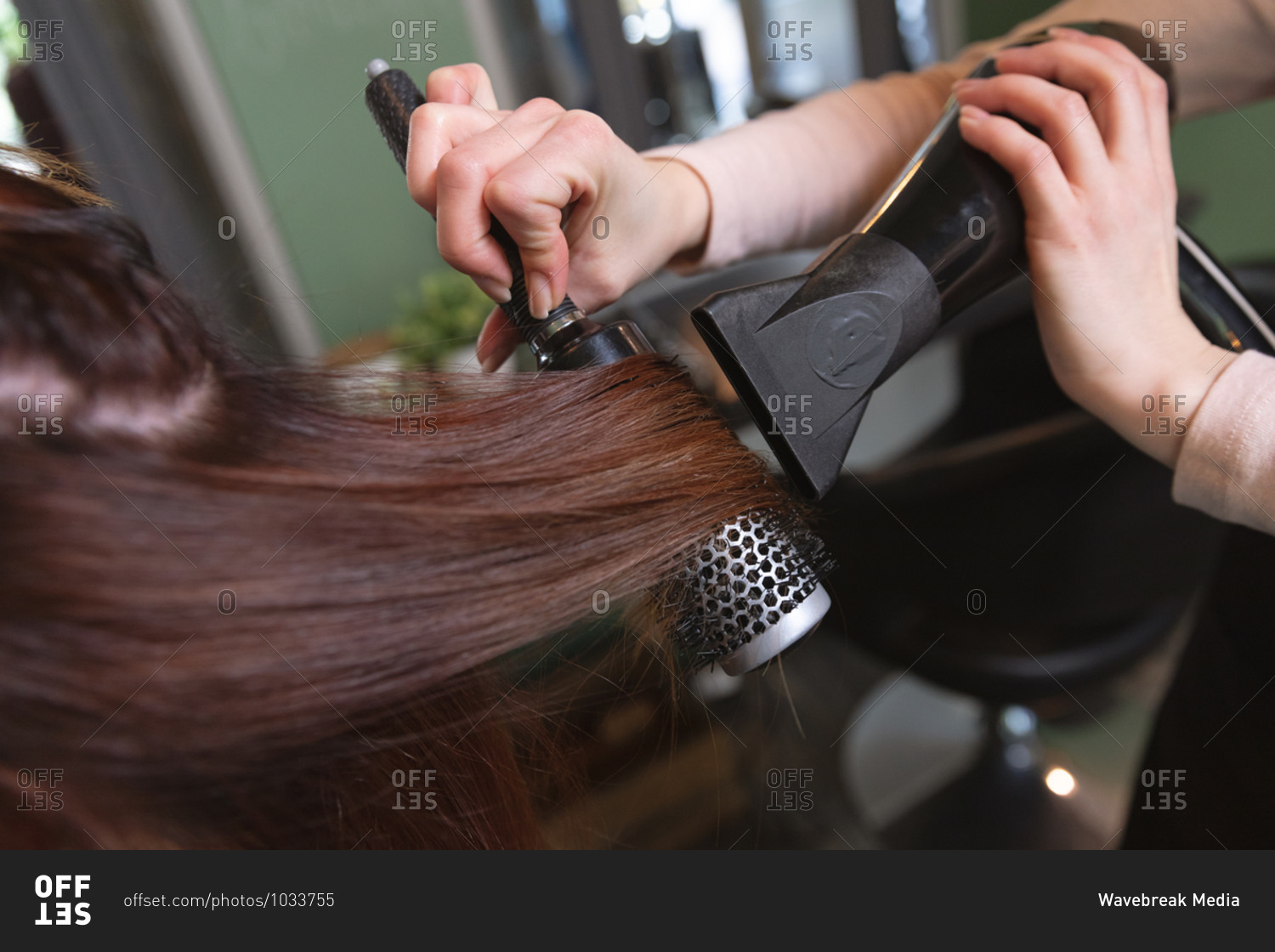 Hands of Caucasian female hairdresser working in hair salon, drying hair of female Caucasian customer. Health and hygiene in workplace during Coronavirus Covid 19 pandemic.