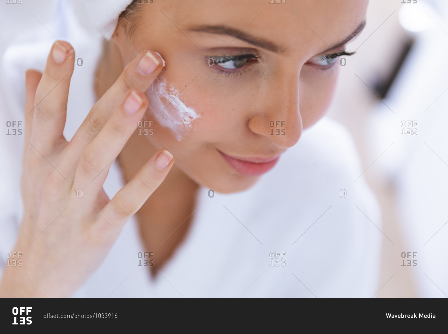 Happy Caucasian woman spending time at home, applying face cream. Social distancing during Covid 19 Coronavirus quarantine lockdown.