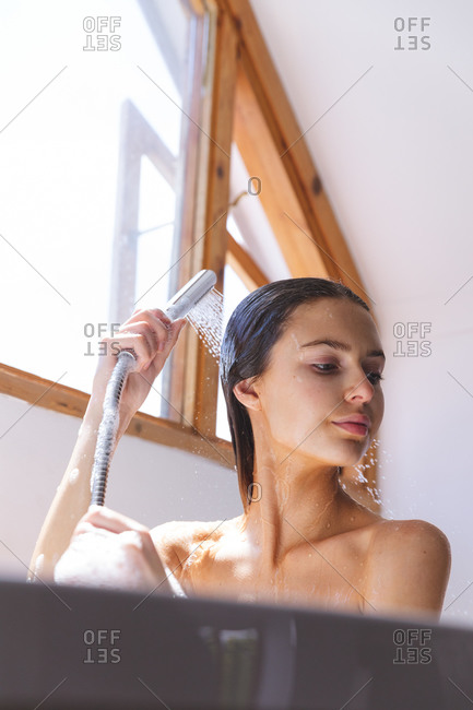 Caucasian woman spending time at home, in bathroom, washing her hair under shower. Social distancing during Covid 19 Coronavirus quarantine lockdown.