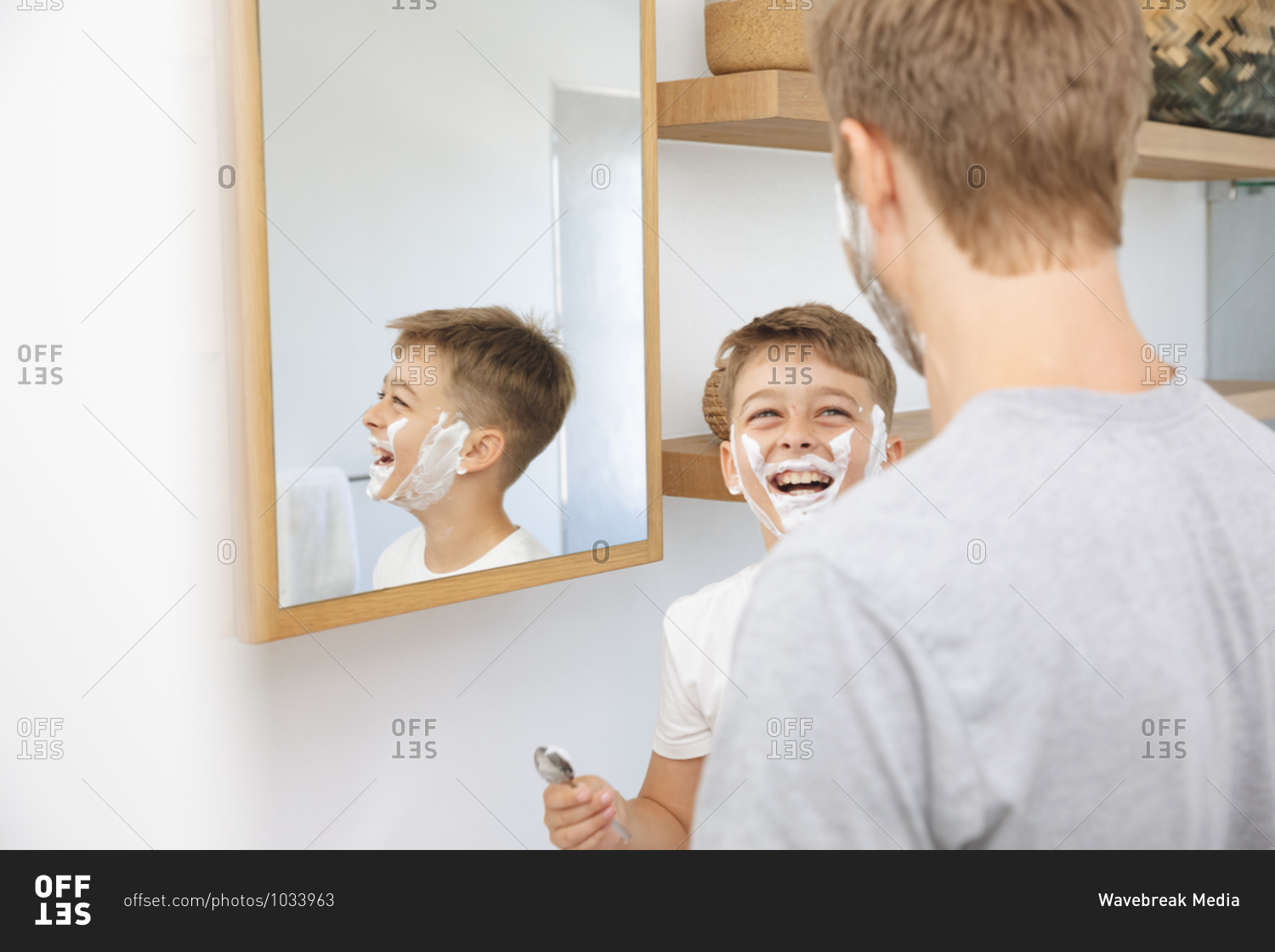 Caucasian man at home with his son together, in bathroom, shaving with shaving cream on faces, smiling. Social distancing during Covid 19 Coronavirus quarantine lockdown.