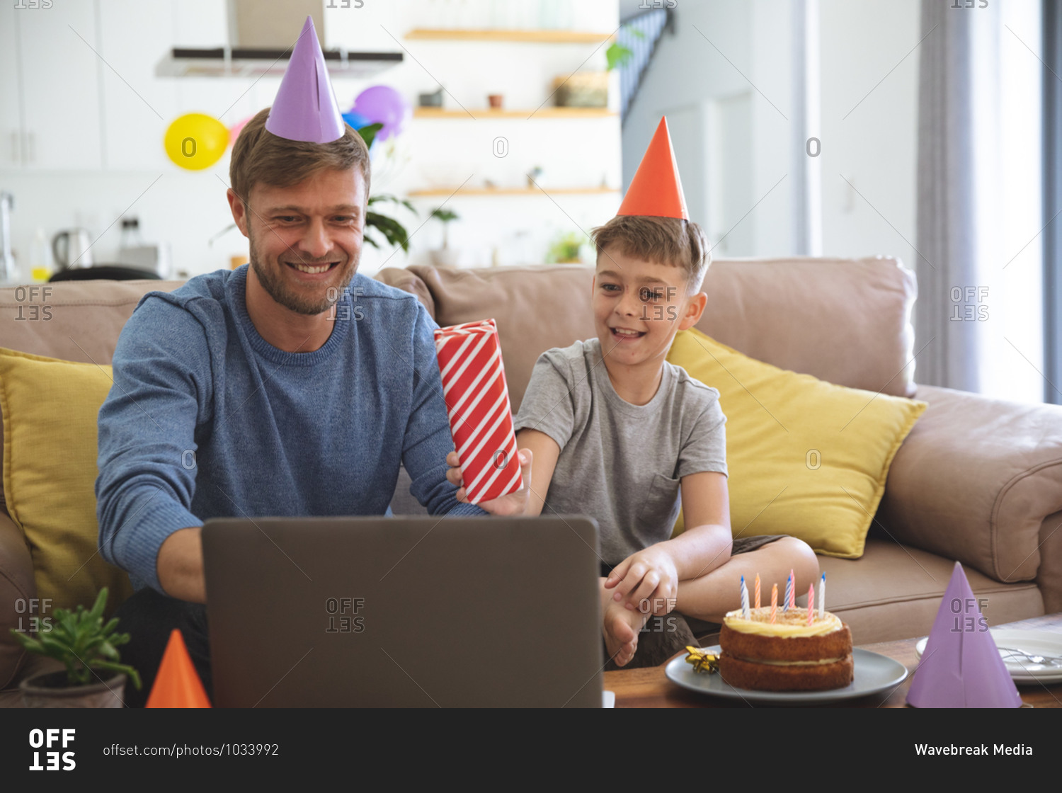 Caucasian man spending time at home with his son together, having birthday party using laptop computer for video chat. Social distancing during Covid 19 Coronavirus quarantine lockdown.