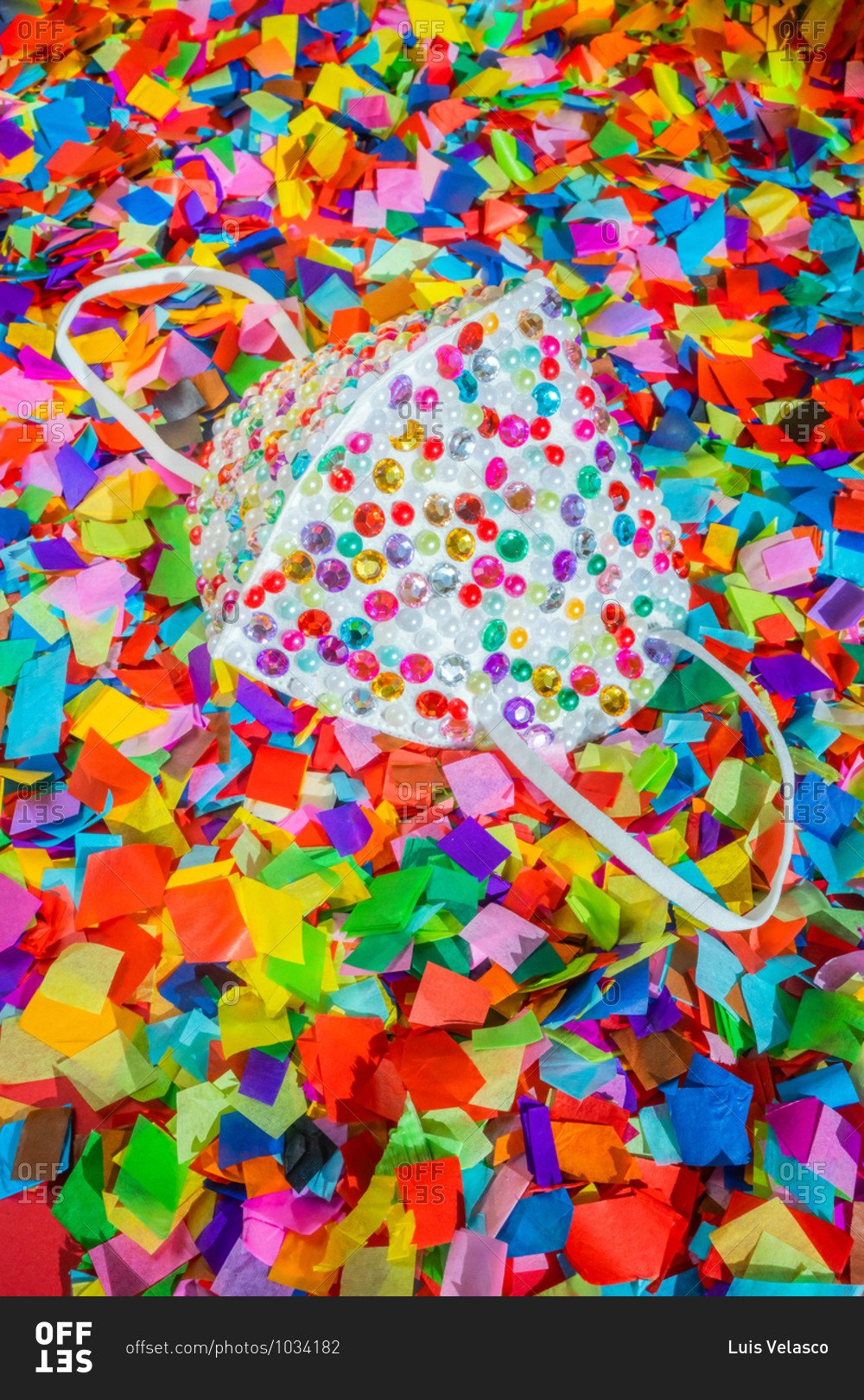 Protective mask covered in sequins and surrounded by confetti