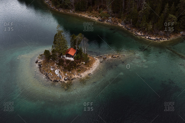 Drone view of breathtaking scenery of small house located on island in calm sea