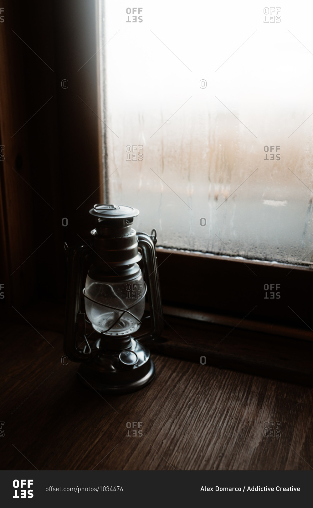 Cozy atmosphere of room with retro oil lantern placed on windowsill with misted window in house