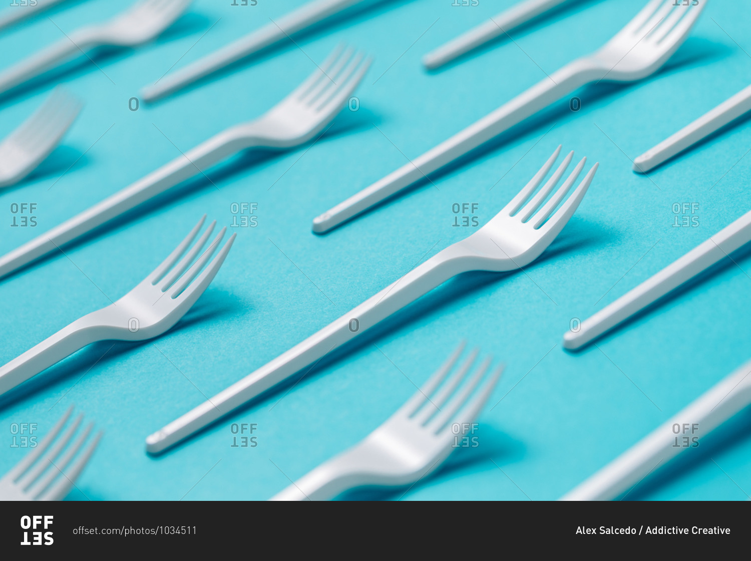 Top view flat lay composition of disposable white plastic forks for takeaway food arranged on blue background