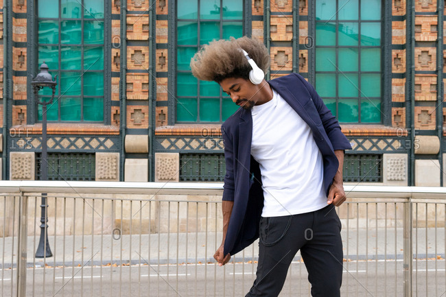 African man dancing while listening to music with a wireless headset in front of a historical building