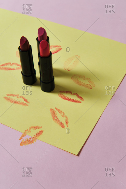 High angle of collection of luxury matte lipsticks placed on two colored background with kiss imprints