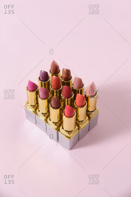 From above of collection of assorted matte lipsticks arranged in rows on pink background in studio