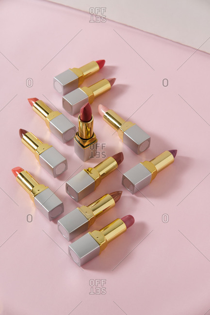 High angle of luxury lipsticks of various colors placed on pink background in studio