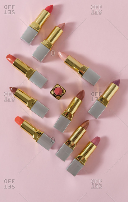 High angle of luxury lipsticks of various colors placed on pink background in studio