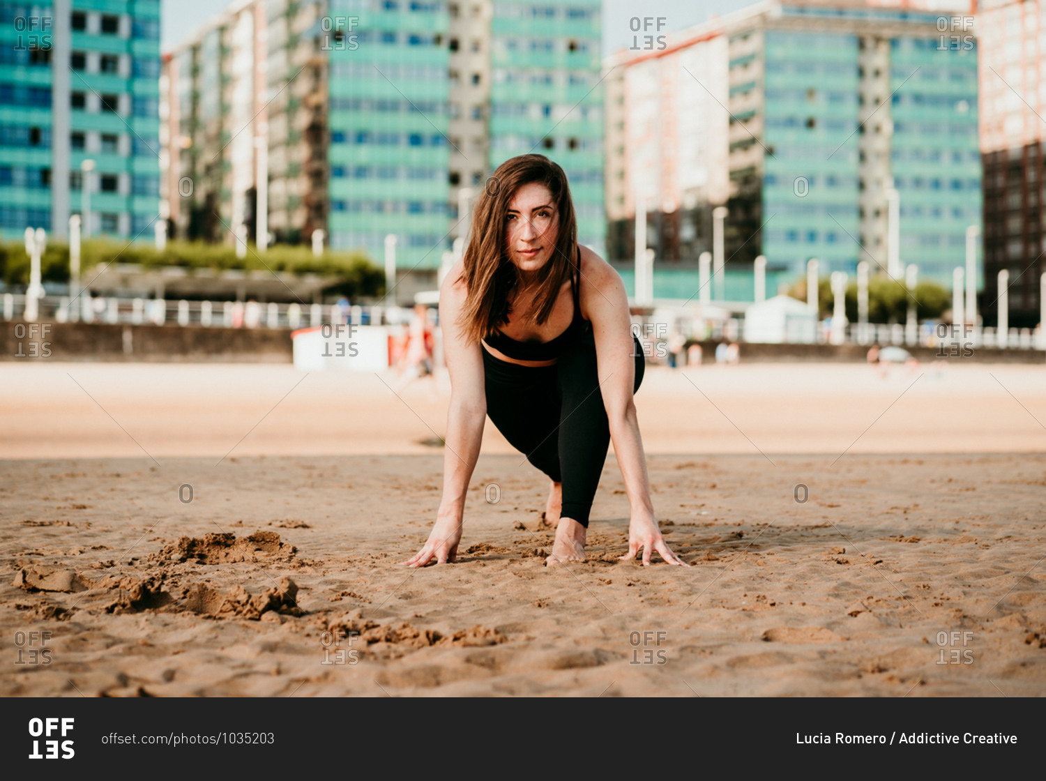 Female standing in High Lunge looking at camera while doing yoga on the beach