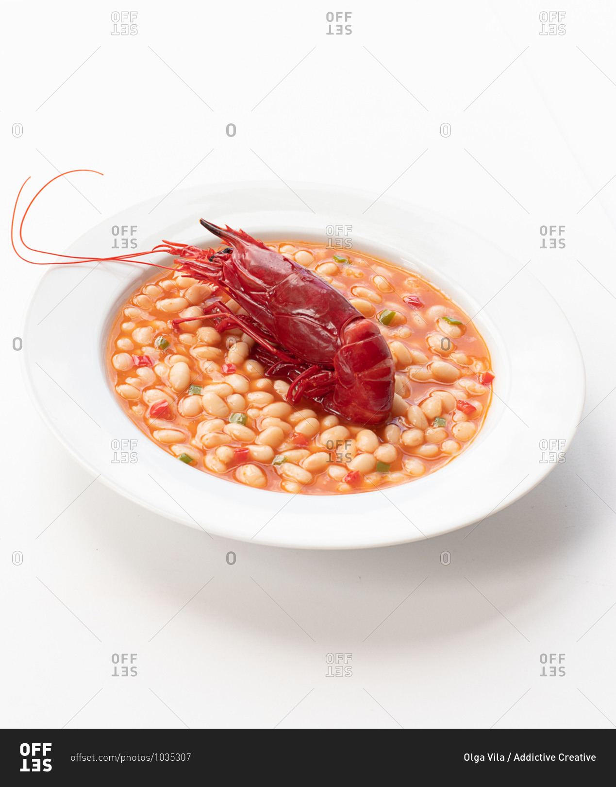 High angle of red boiled crawfish placed in bowl with beans in tomato sauce and served on table in cafe
