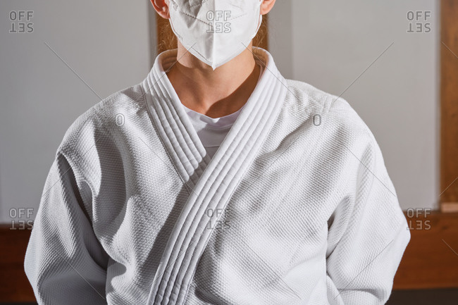 Cropped unrecognizable person with a white kimono and a mask indoors