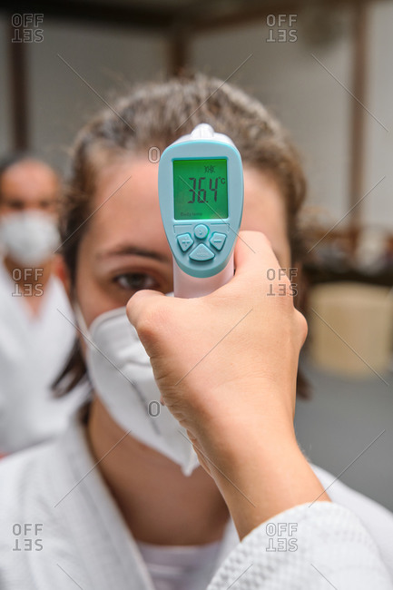Temperature test machine in front of a row of people wearing a kimono and mask in a krav maga gym