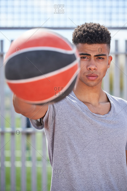 Young determined African American male player standing with basketball on sports ground and looking at camera