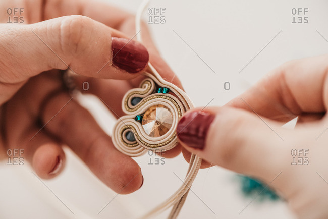 Closeup of crop skilled craftswoman creating soutache bijouterie with threads and beads in bright workshop