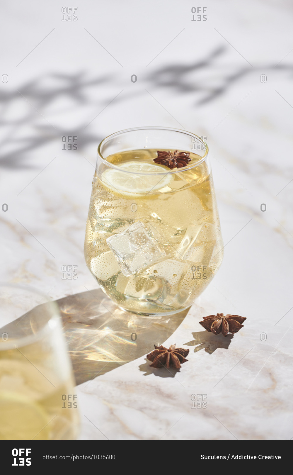 High angle of delicious cocktails with lemon slices and ice cubes garnished with star anise and served on marble table