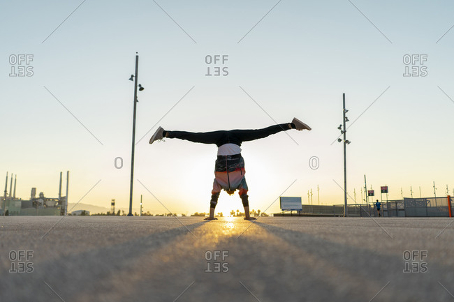 Acrobat doing handstand in the city at sunrise