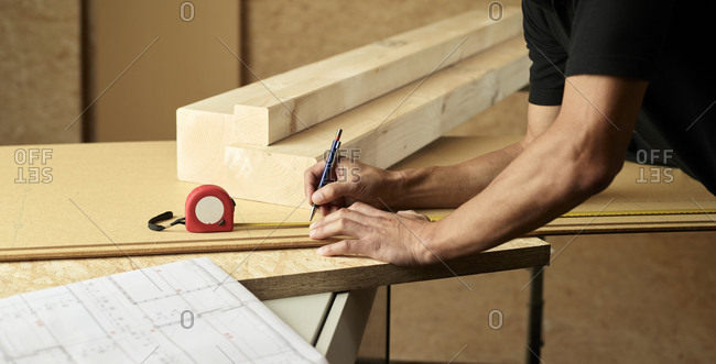 Worker marking wood with pencil- tape measure