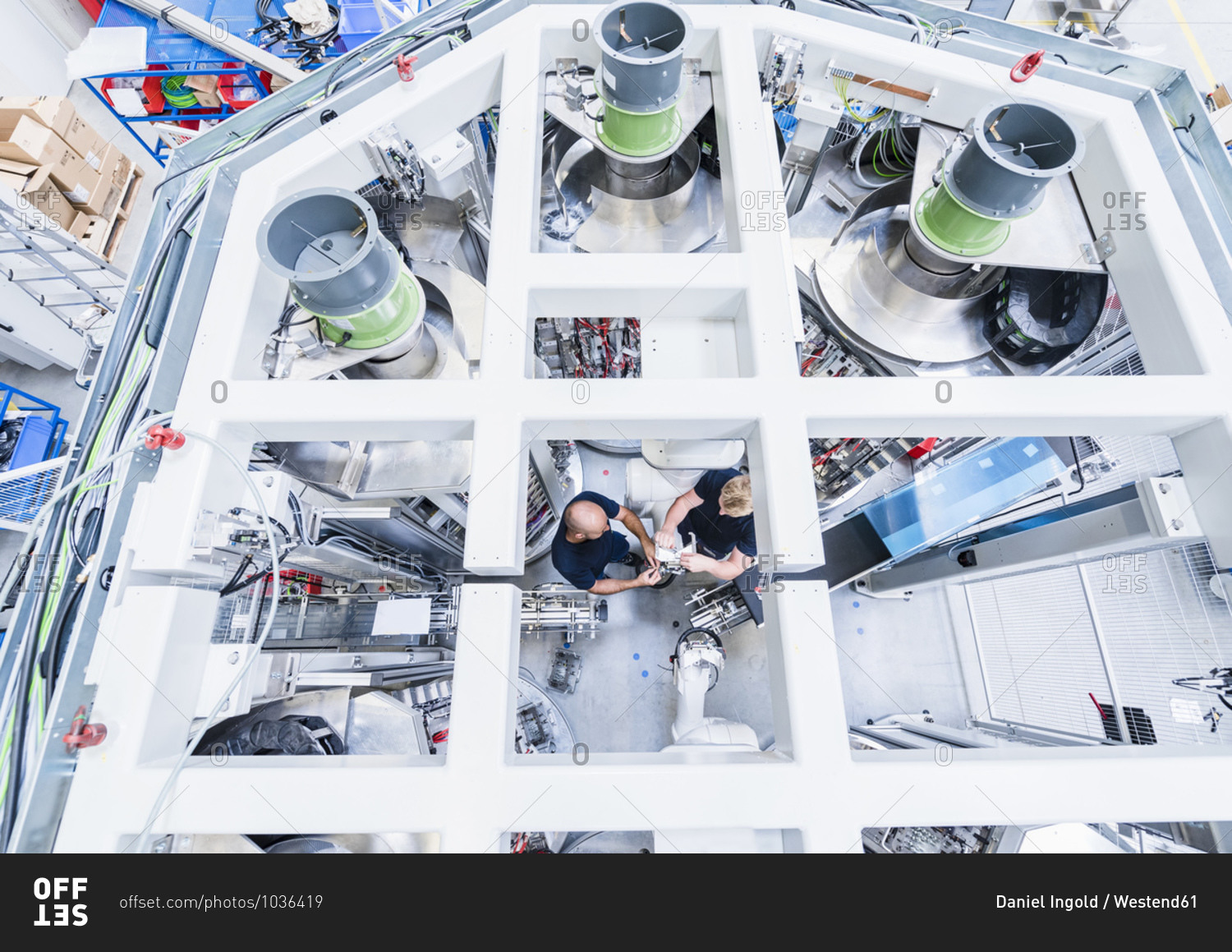 Top view of two colleagues working at industrial robot in modern factory