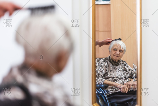 Woman taking care of old woman brushing her hair