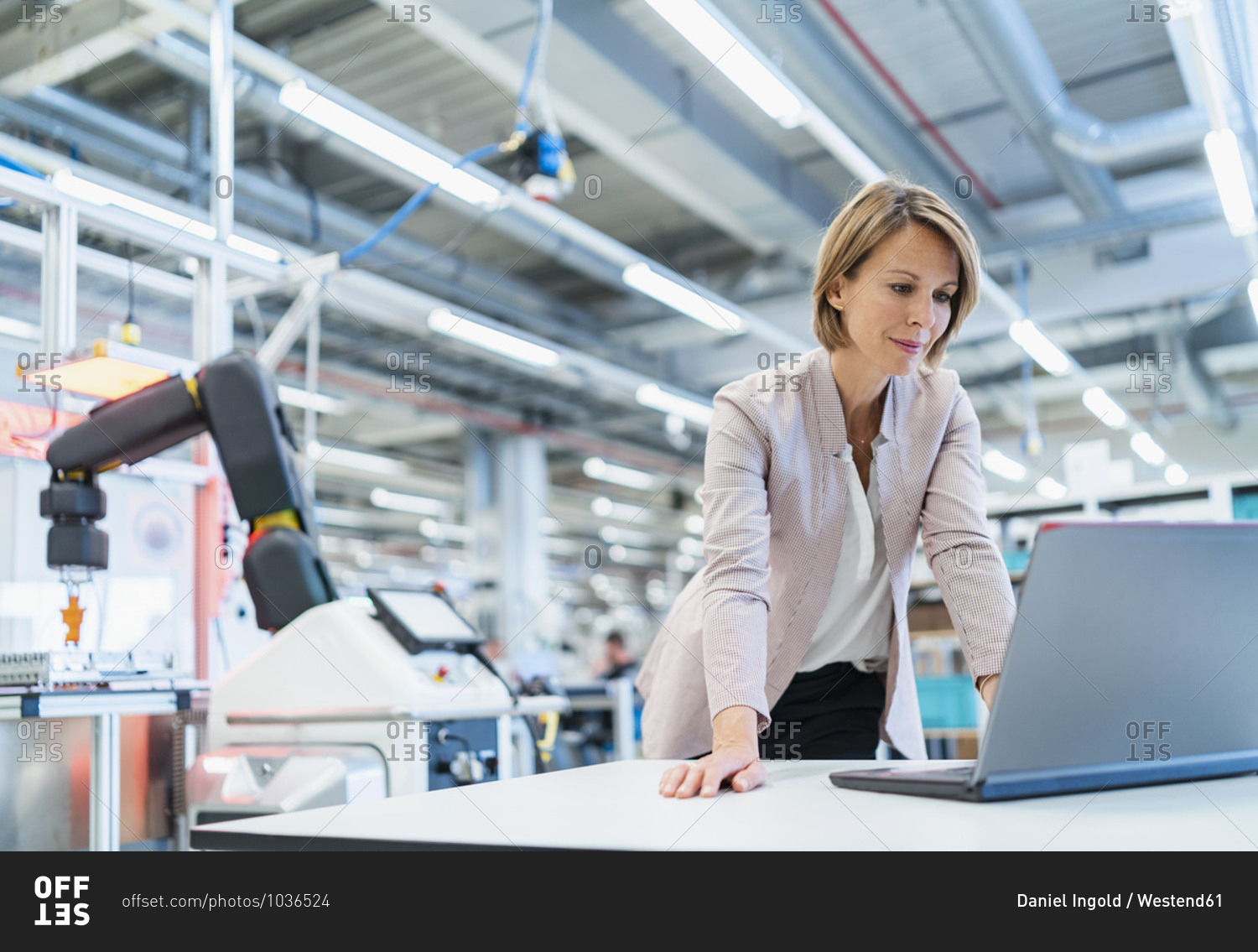 Businesswoman in a modern factory hall using laptop