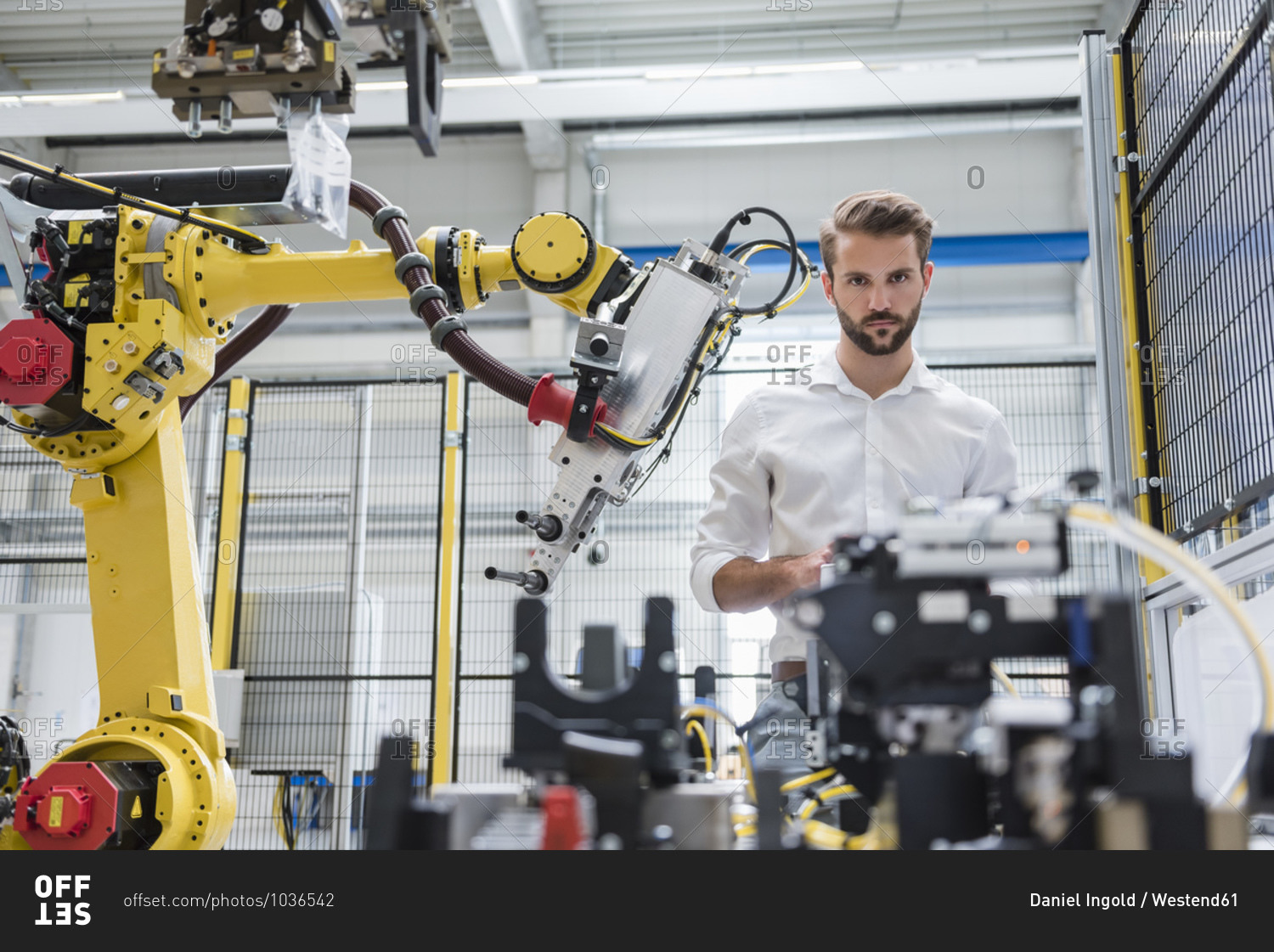 Confident male robotics expert looking at machinery in\
automated industry stock photo - OFFSET