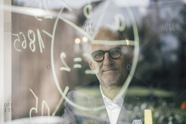 senior businessman brainstorming- drawing formulas on window pane