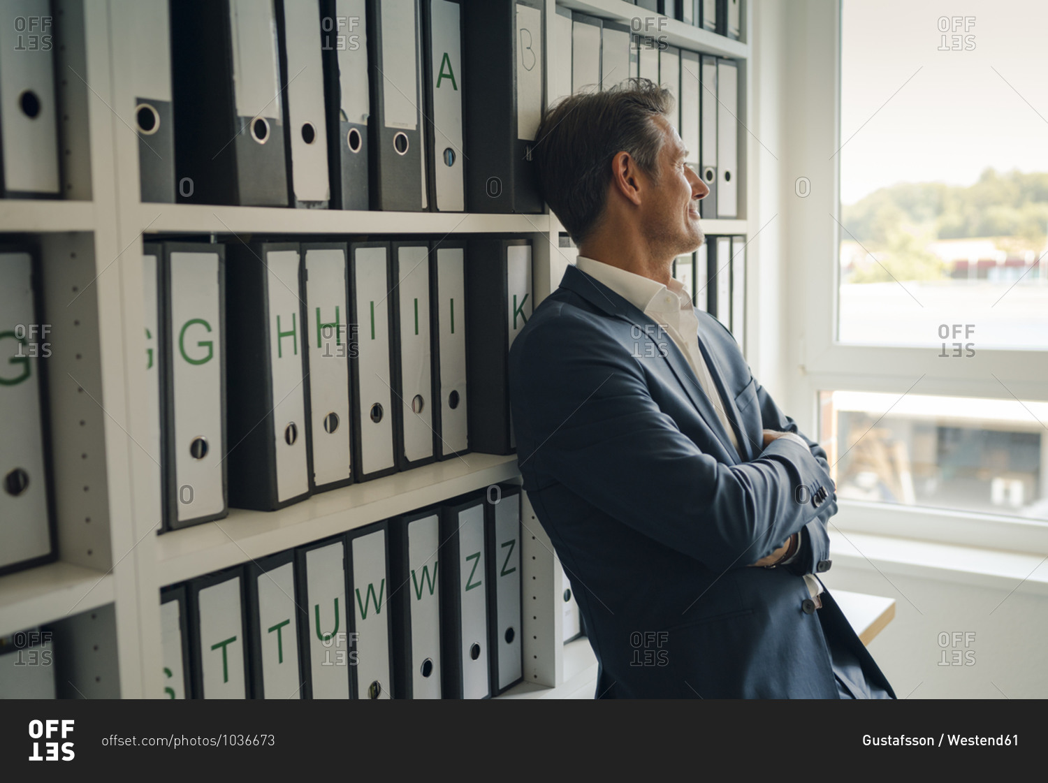 Businessman in company archive- leaning against shelf with files