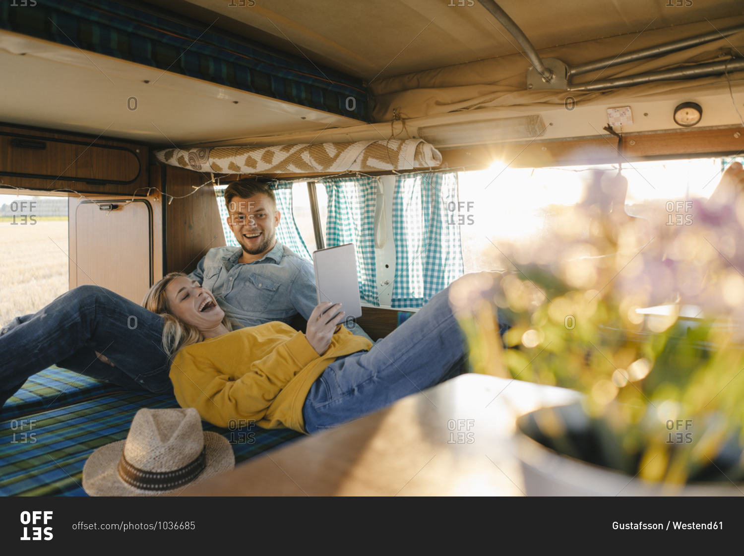 Happy young couple looking at tablet inside camper van