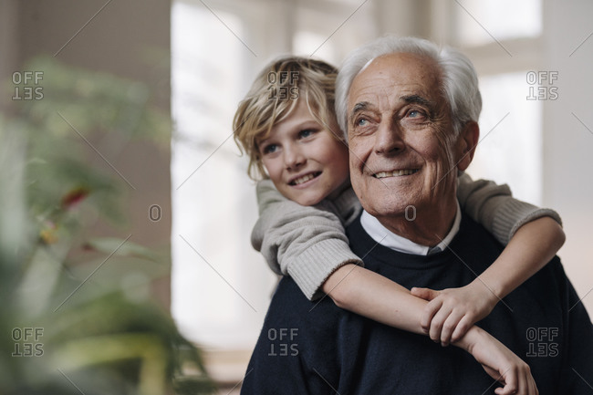 Happy grandson embracing grandfather at home