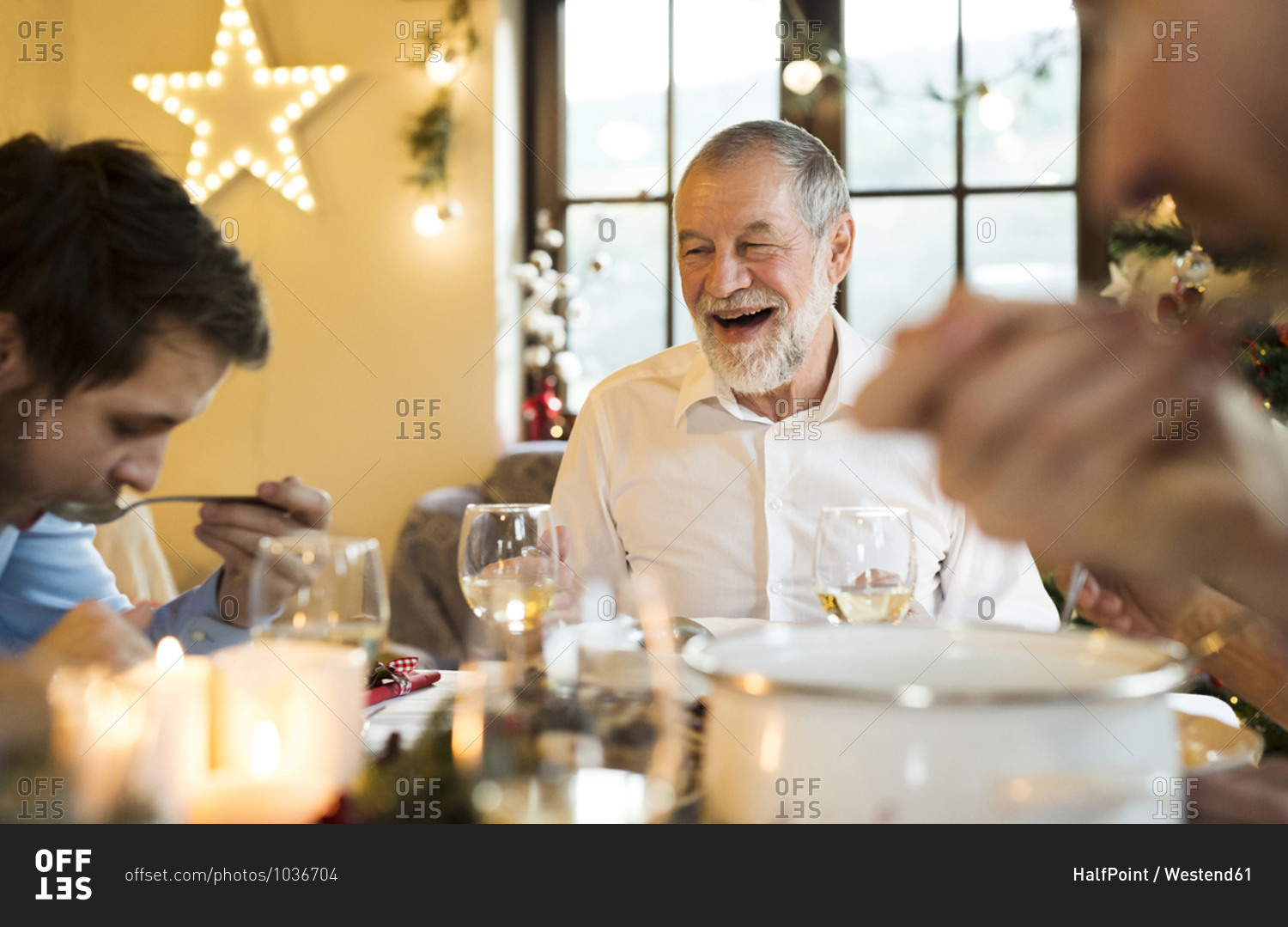 Happy senior man looking at adult son at Christmas dinner table