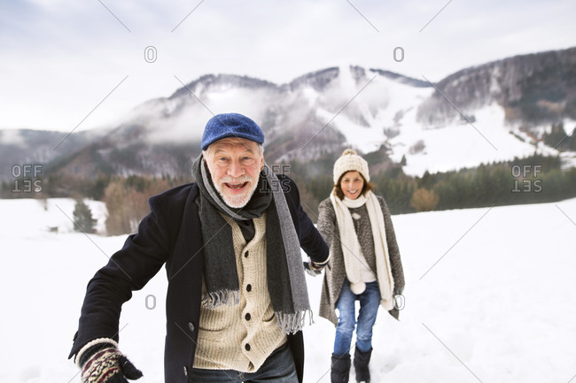 Portrait of senior man walking hand in hand with his wife in snow-covered landscape