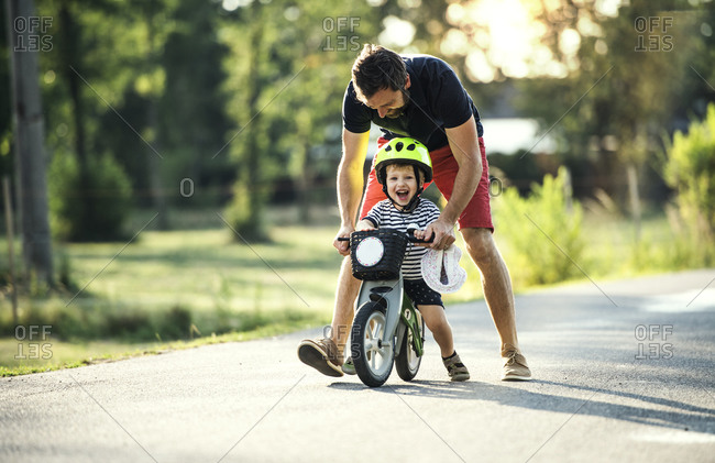 Father teaching little son riding bicycle