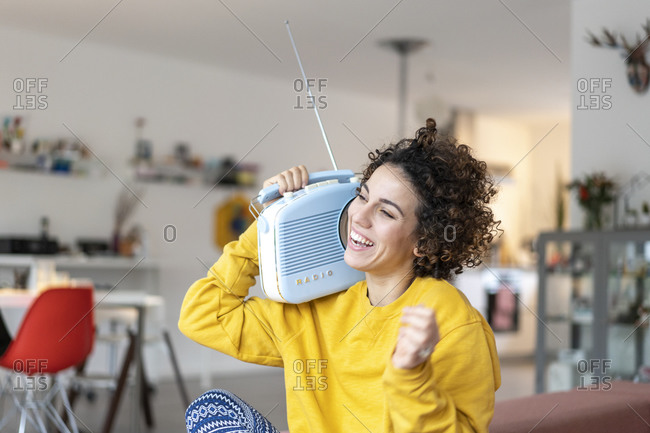 Carefree woman listening to music with portable radio at home
