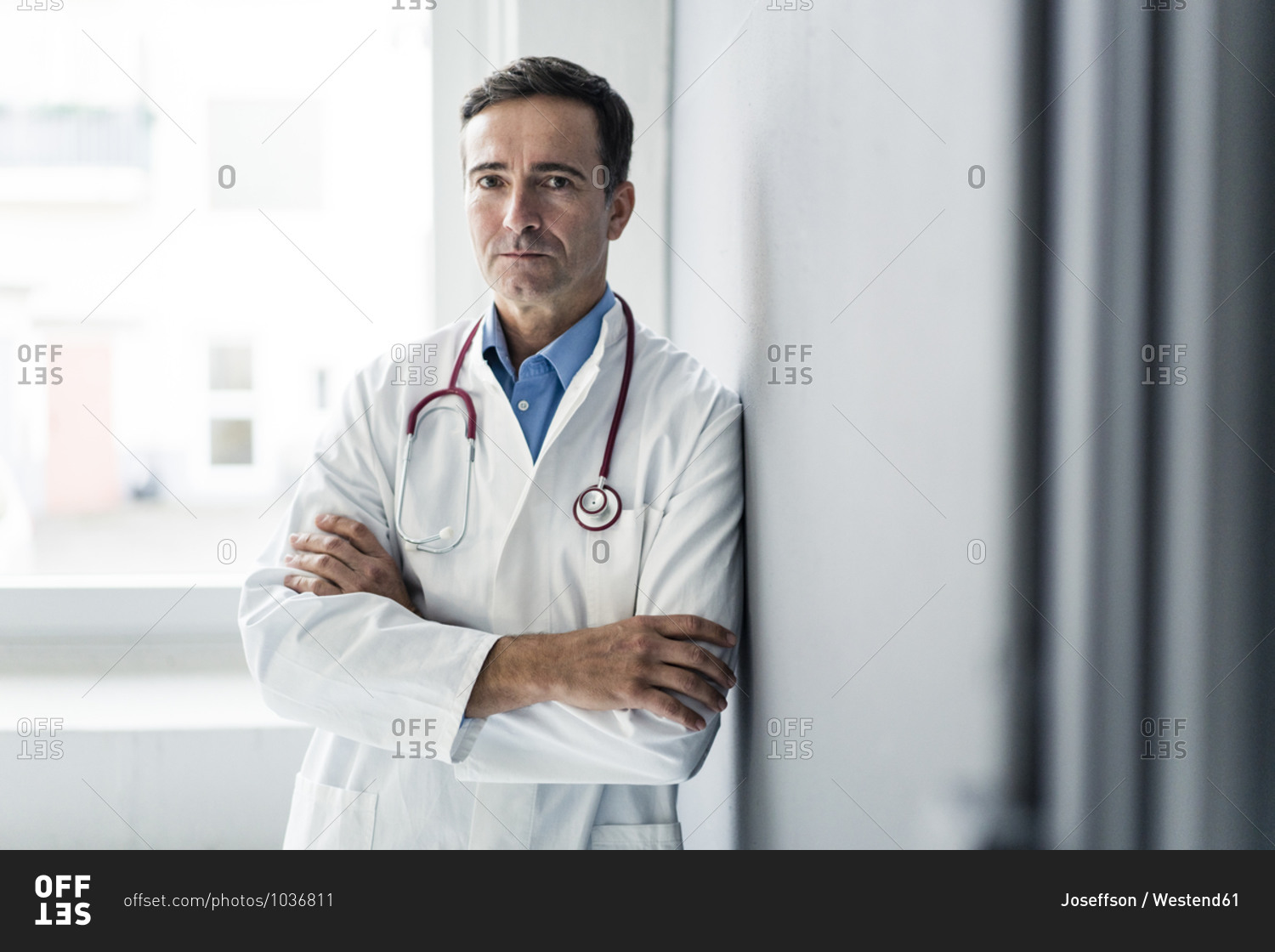 Portrait of serious doctor leaning against a wall