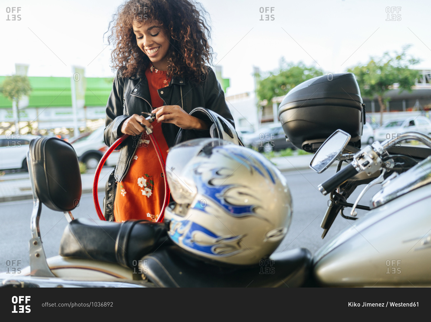 Smiling young woman removing safety lock from her motorcycle