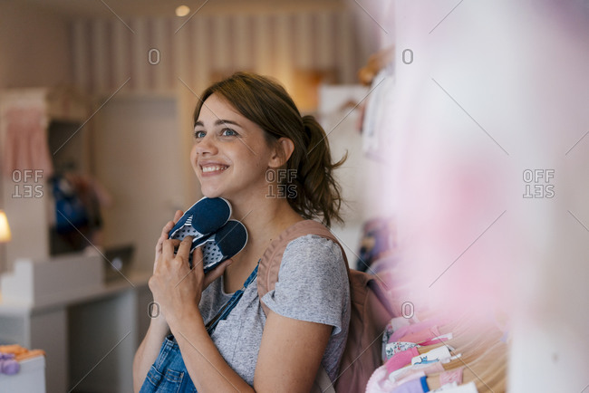 Smiling pregnant woman shopping for baby clothing in a boutique