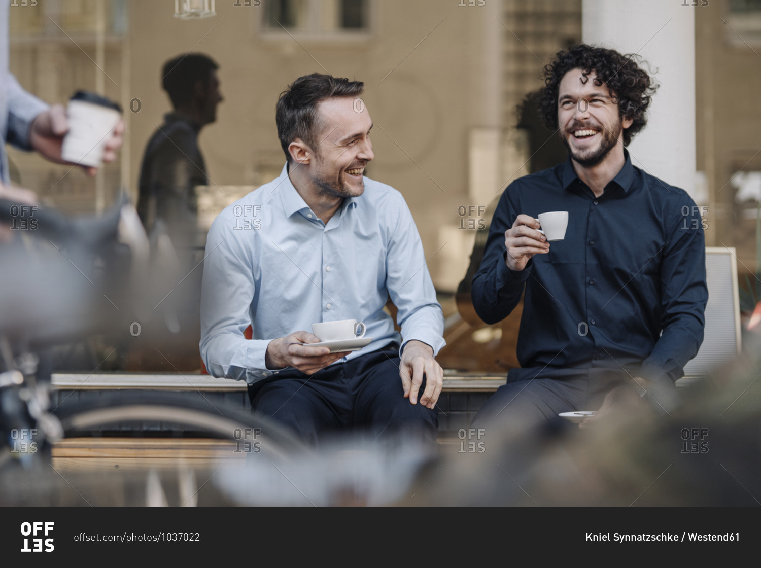 Friends sitting in front of coffee shop- talking- drinking coffee